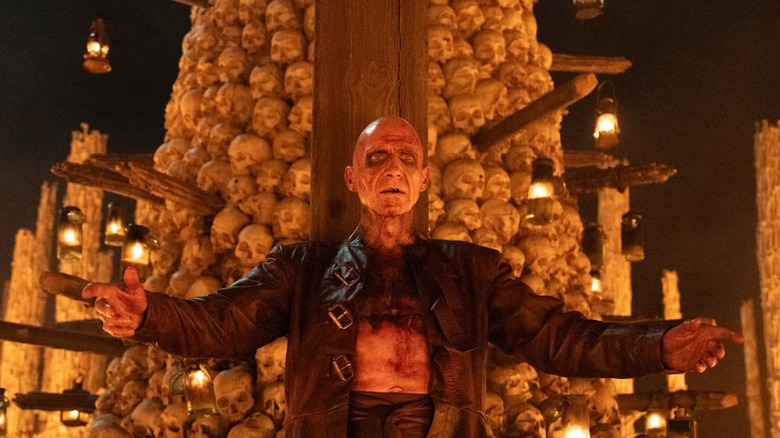 Dr. Ian Kelson, dressed as Old Nick, stands in front of skulls in 28 Years Later: The Temple of Bones