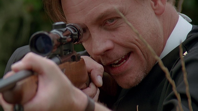 Mark Hamill as Reverend George staring down the barrel of his rifle in Village of the Damned (1995)