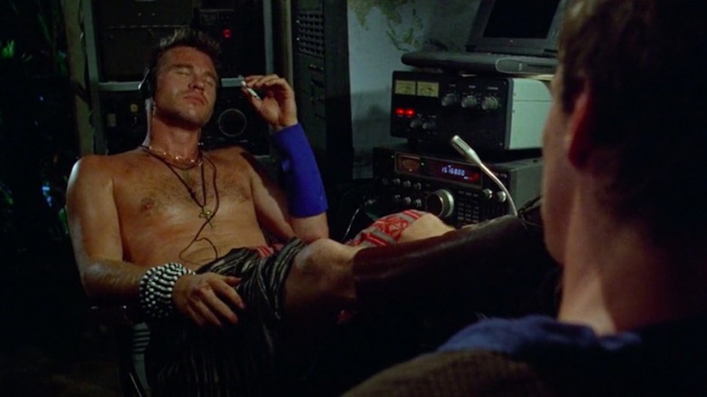 A shirtless Val Kilmer enjoys a cigarette as Dr. Montgomery in The Island of Dr. Moreau