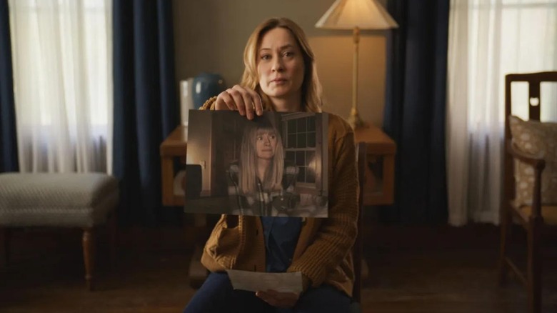Camille Sullivan as Mia holding up a picture of Riley in Shelby Oaks