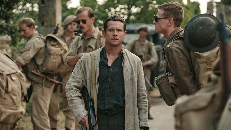 Jack O'Connell walking past soldiers with a gun