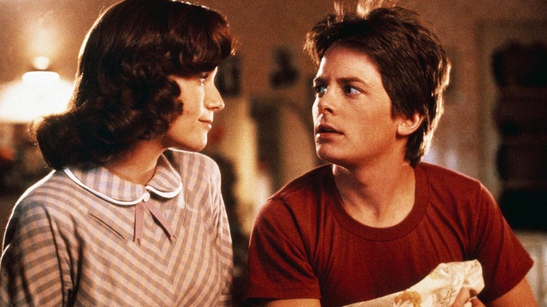 Marty sitting on the bed with Lorraine in her room in Back to the Future