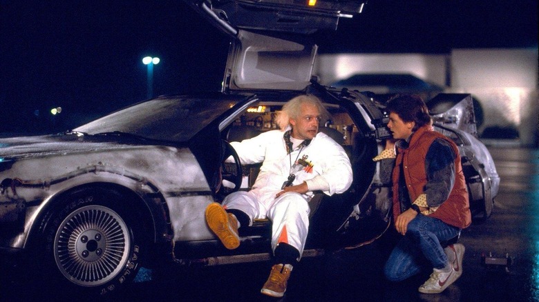Doc Brown sitting in the DeLorean while Marty crouches by the door in Back to the Future