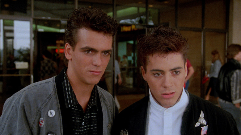 Robert Rusler as Max and Robert Downey Jr. as Ian standing in front of their high school in Weird Science