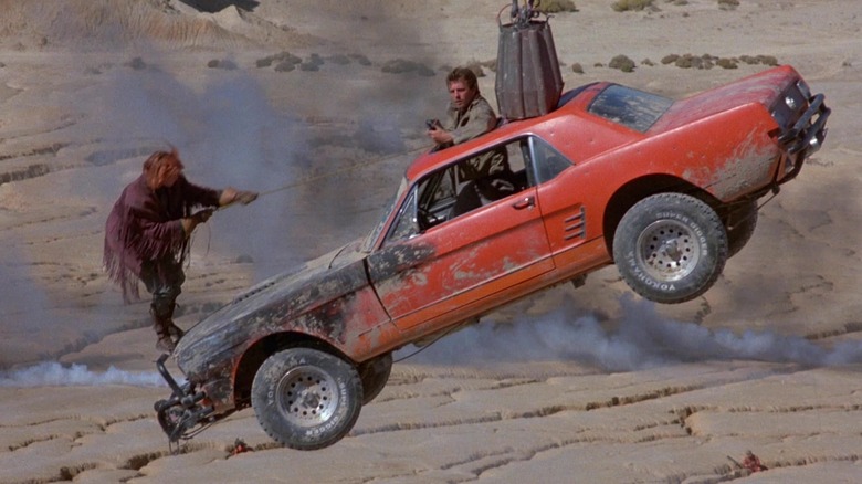 Melanie Griffith as Edith "E" Johnson and David Andrews as Sam Treadwell are in a car that's been hoisted in the air in Cherry 2000