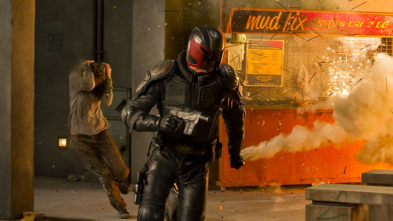 Karl Urban as Judge Dredd running away from an explosion in Dredd