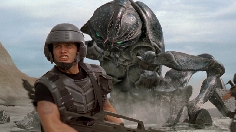 Casper Van Dien as Johnny Rico with a giant bug behind him in Starship Troopers