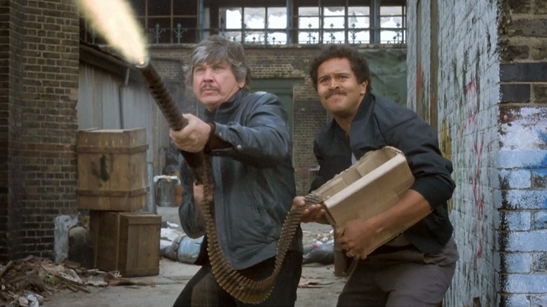 Paul Kersey firing a machine gun with Mr. Martinez's help in Death Wish 3