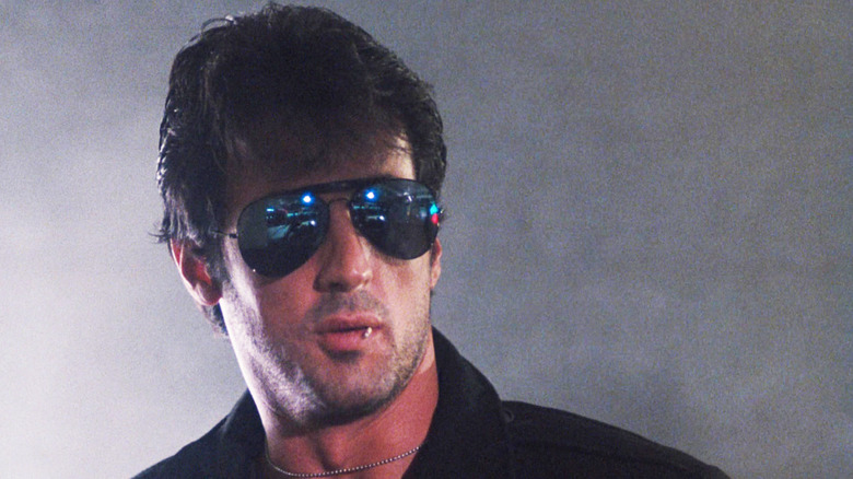 Sylvester Stallone as Lieutenant Marion "Cobra" Cobretti is seen in closeup standing amid smoke in Cobra