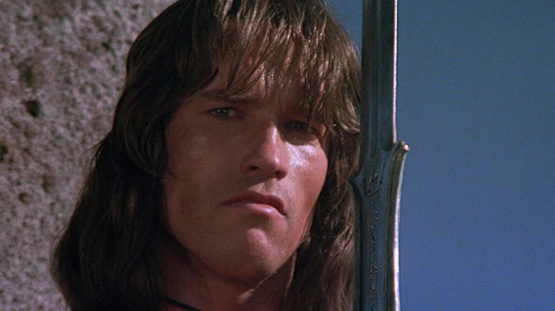 Arnold Schwarzenneger's Conan is seen in closeup holding a sword in Conan the Barbarian
