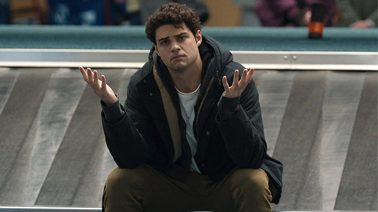 Noah Centineo as Owen Hendricks sitting on an airport baggage claim track in The Recruit