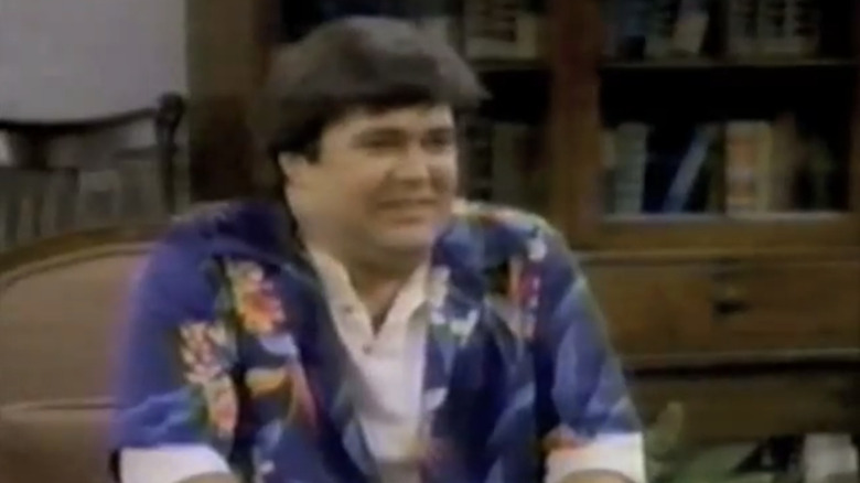 Kevin Meaney as Buck Russell sits in a living room in Uncle Buck