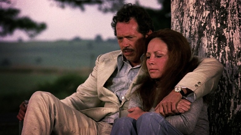 Bennie (Warren Oates) and Elita (Isela Vega) sitting against a tree in "Bring Me the Head of Alfredo Garcia."