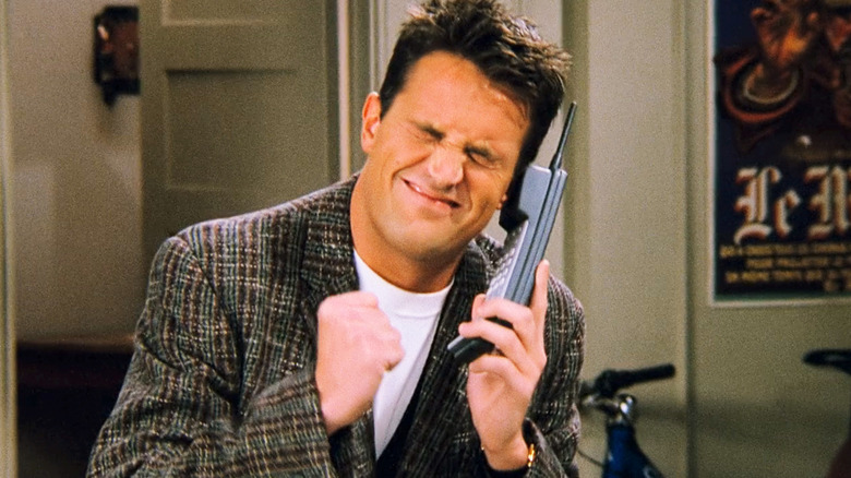 Matthew Perry's Chandler Bing grimaces as he holds a phone in Friends