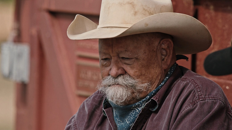 Barry Corbin's Ross sits outside looking down in Yellowstone