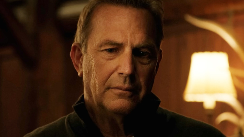 Kevin Costner's John Dutton looks down in closeup as he stands in his cabin in Yellowstone