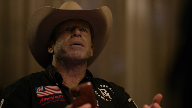 Taylor Sheridan's Travis Wheatley looks up with his cellphone in hand as he sits at a poker game in Yellowstone