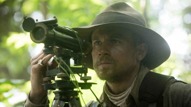 Percy Fawcett looking through a cartography instrument in the jungle in The Lost City of Z