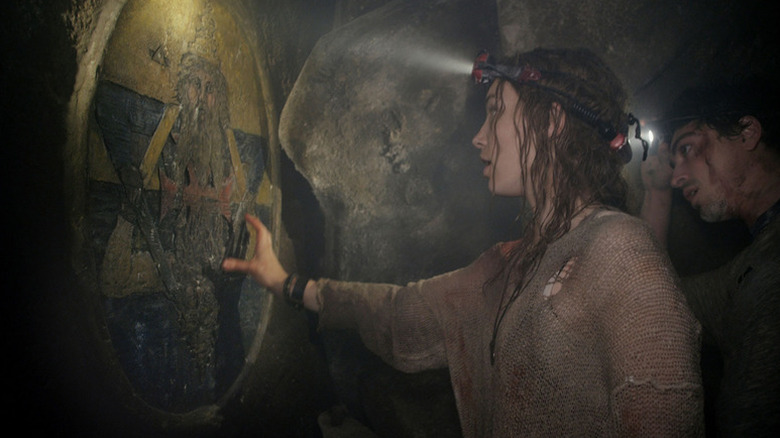 Scarlett looking at a symbol on a wall in As Above, So Below
