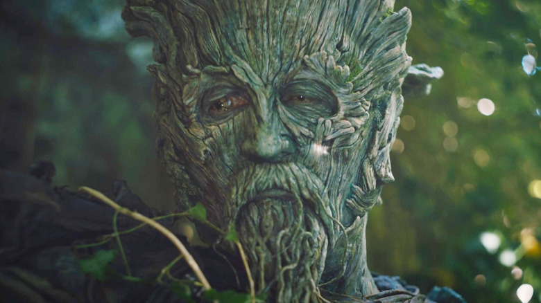 The Green Knight standing next to some trees in The Green Knight (2021)