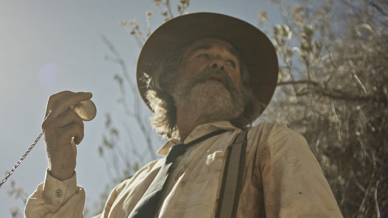 Kurt Russell's Sheriff Franklin Hunt holds up a pocket watch as he looks off into the distance in Bone Tomahawk