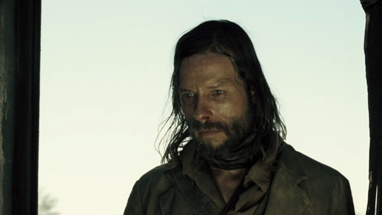 Guy Pearce's Charlie Burns stands looking worried in a doorway in The Proposition