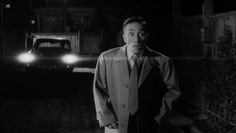 A man about to be run down by a car in The Bad Sleep Well