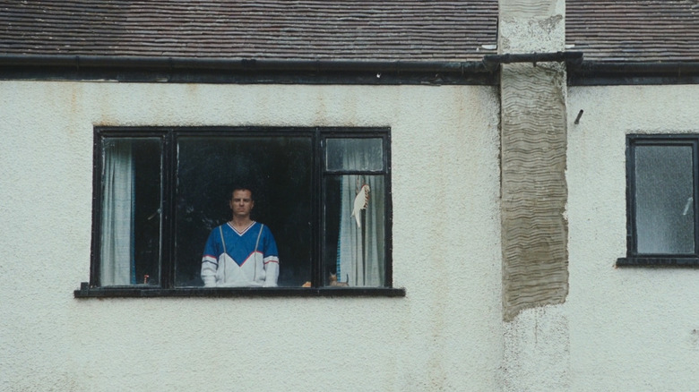 Andrew Scott's Adam looks. out from the window of a suburban home in All of Us Strangers