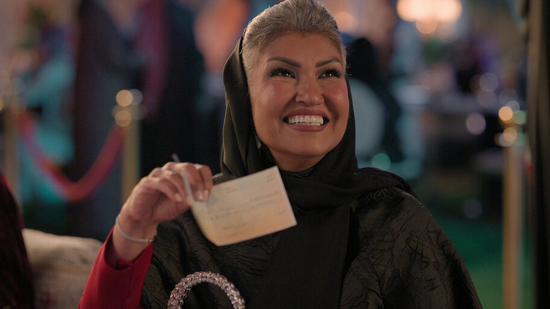 Alanoud holding up a check in Crazy Rich, Incredibly Broke