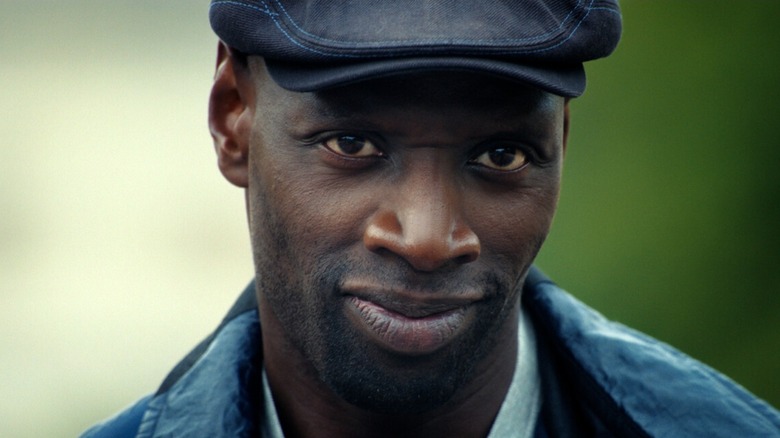 Assane wearing a cap and smirking in Lupin