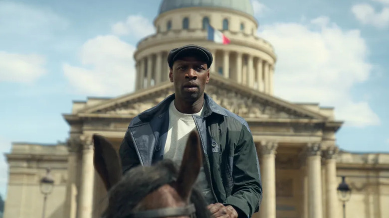 Assane riding a horse in front of the Assemblee National in Lupin