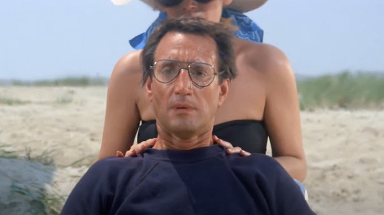 Martin Brody sitting in chair on beach, looking alarmed, with Ellen Brody behind him in Jaws