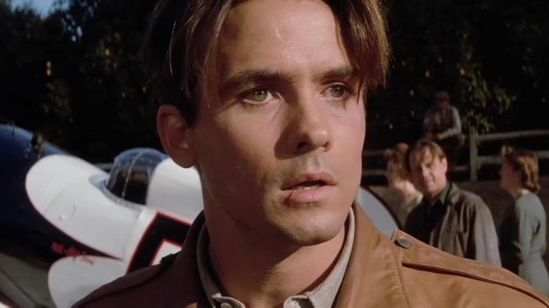 Bill Campbell as Cliff Secord looking surprised next to an airplane in The Rocketeer