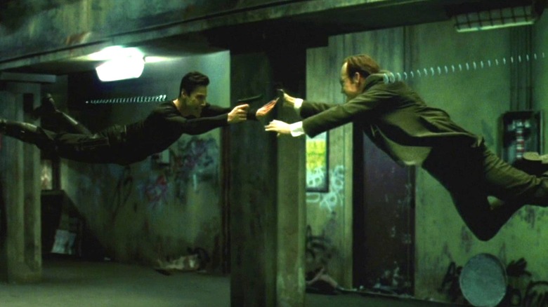 Keanu Reeves as Neo and Hugo Weaving as Agent Smith hanging in the air as the fire bullets at one another in The Matrix