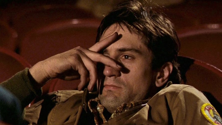 Travis Bickle watching a movie through his fingers in Taxi Driver