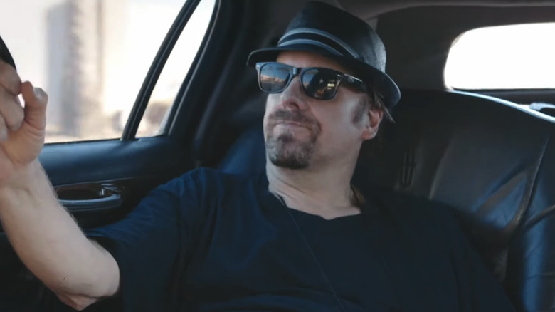 The Amazing Johnathan sits in a car wearing shades in The Amazing Johnathan Documentary