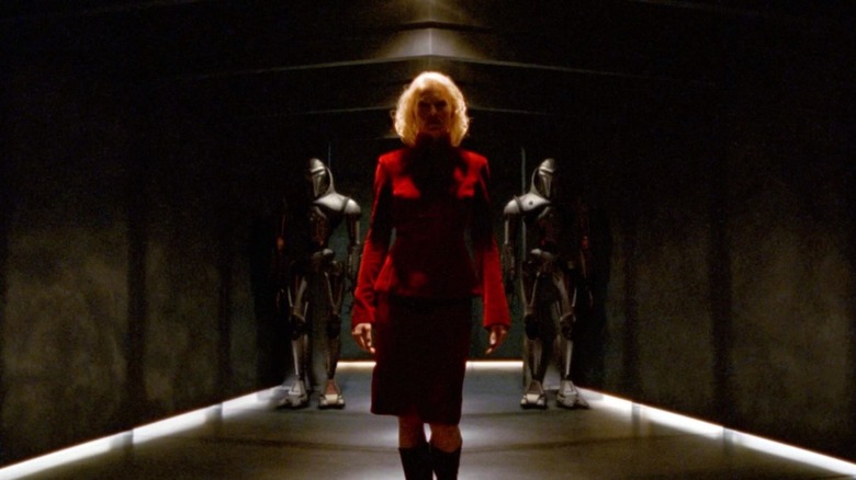 Number Six (Tricia Helfer) walking down hallway with two Cylon Centurions beside her in Battlestar Galactica