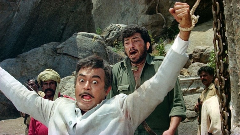A man in a white suit, chained and panicked, a screaming man behind him in Sholay