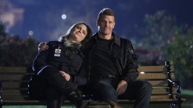 Emily Deschanel as Temperance Brennan and David Boreanaz as Seeley Booth sitting on a bench on Bones