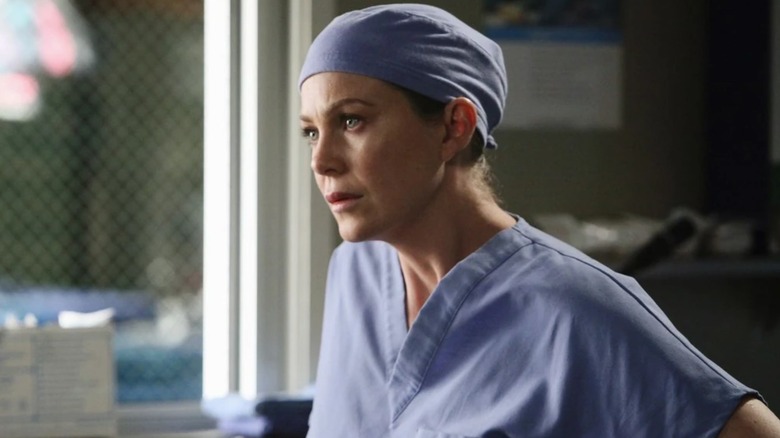 Meredith in the scrub room wearing a scrub cap looking concerned on Grey's Anatomy