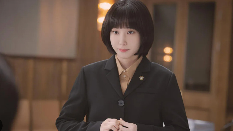 Woo Young-woo (Park Eun-bin) stands in a room with her fingers knitted in Extraordinary Attorney Woo