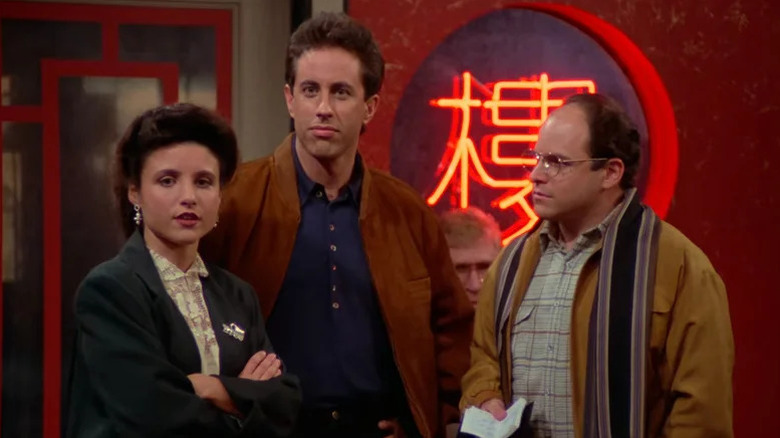 Julia Louis-Dreyfus as Elaine, Jerry Seinfeld as Jerry, and Jason Alexander as George standing in a Chinese restaurant on Seinfeld