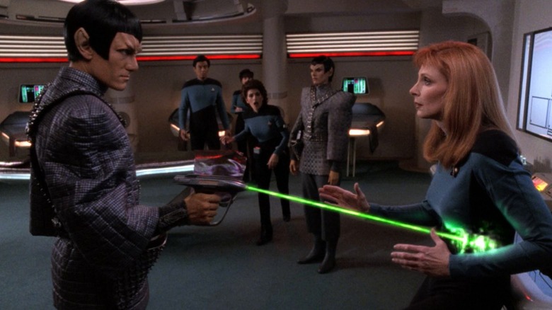 A Romulan shooting Dr. Crusher while Troi looks on in Star Trek: The Next Generation