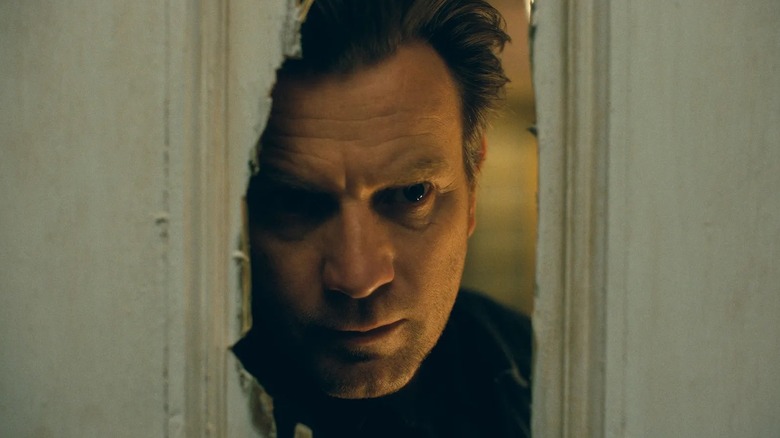 Danny Torrance (Ewan McGregor) looking through a hole in the door in Doctor Sleep