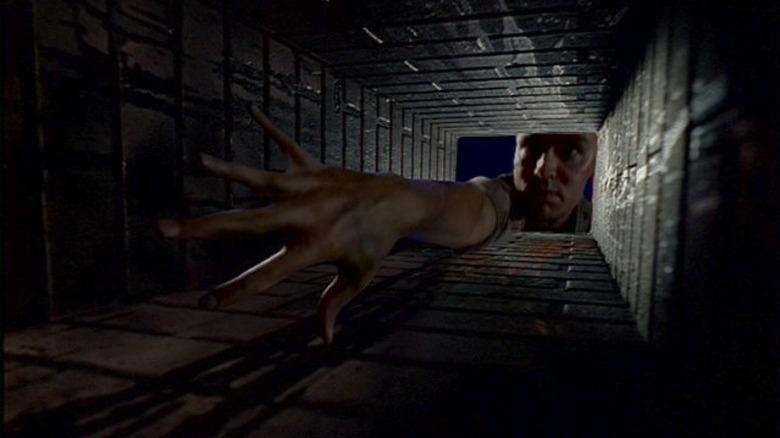 Tooms reacing his strecthy arm down a brick shaft on The X-Files