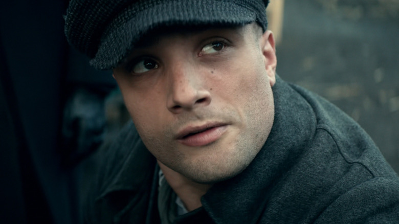 Cosmo Jarvis as Barney Thompson wearing a hat and looking up in Peaky Blinders