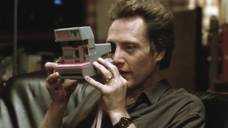 Whitley Streiber holding a Polaroid camera to his eye in Communion