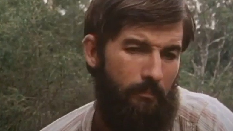 Ned Kelly (John Jarratt) sits thoughtfully with a full beard in The Last Outlaw