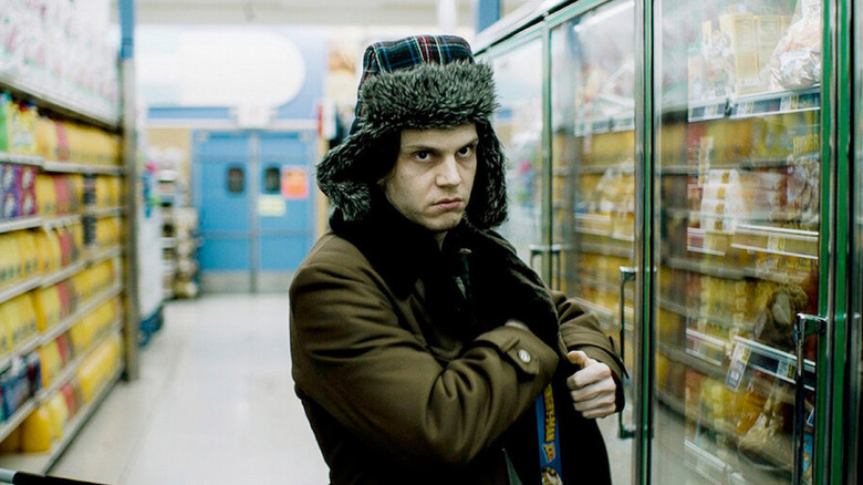 Evan Peters as Warren Lipka stuffing a TV dinner in his jacket in American Animals