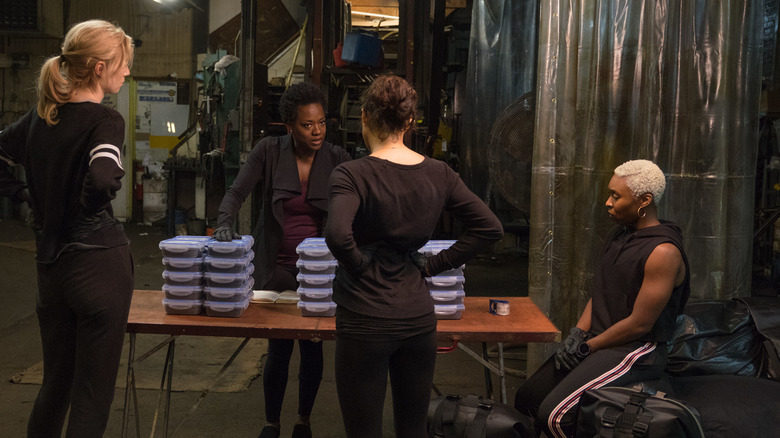 Allice, Linda, and Belle standing around the table listening to Veronica talk in Widows